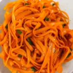 Alt Text: Chili crisp carrot ribbon salad in rustic bowl