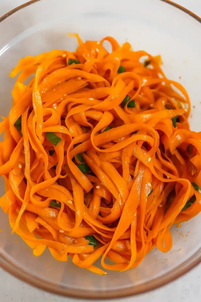 Alt Text: Chili crisp carrot ribbon salad in rustic bowl